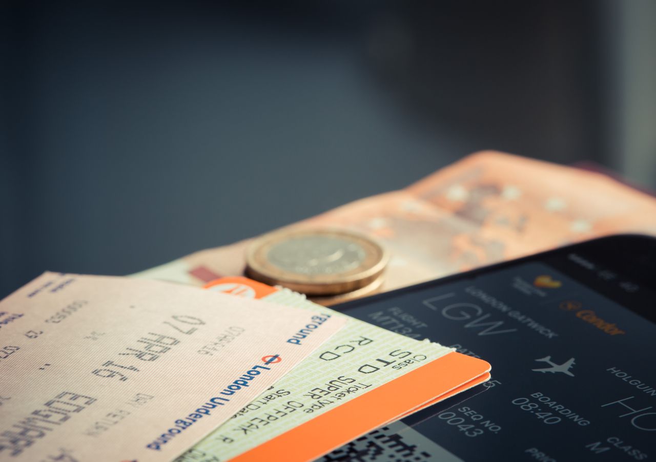 Hand holding passport and tickets by airplane window, preparing for travel adventure.
